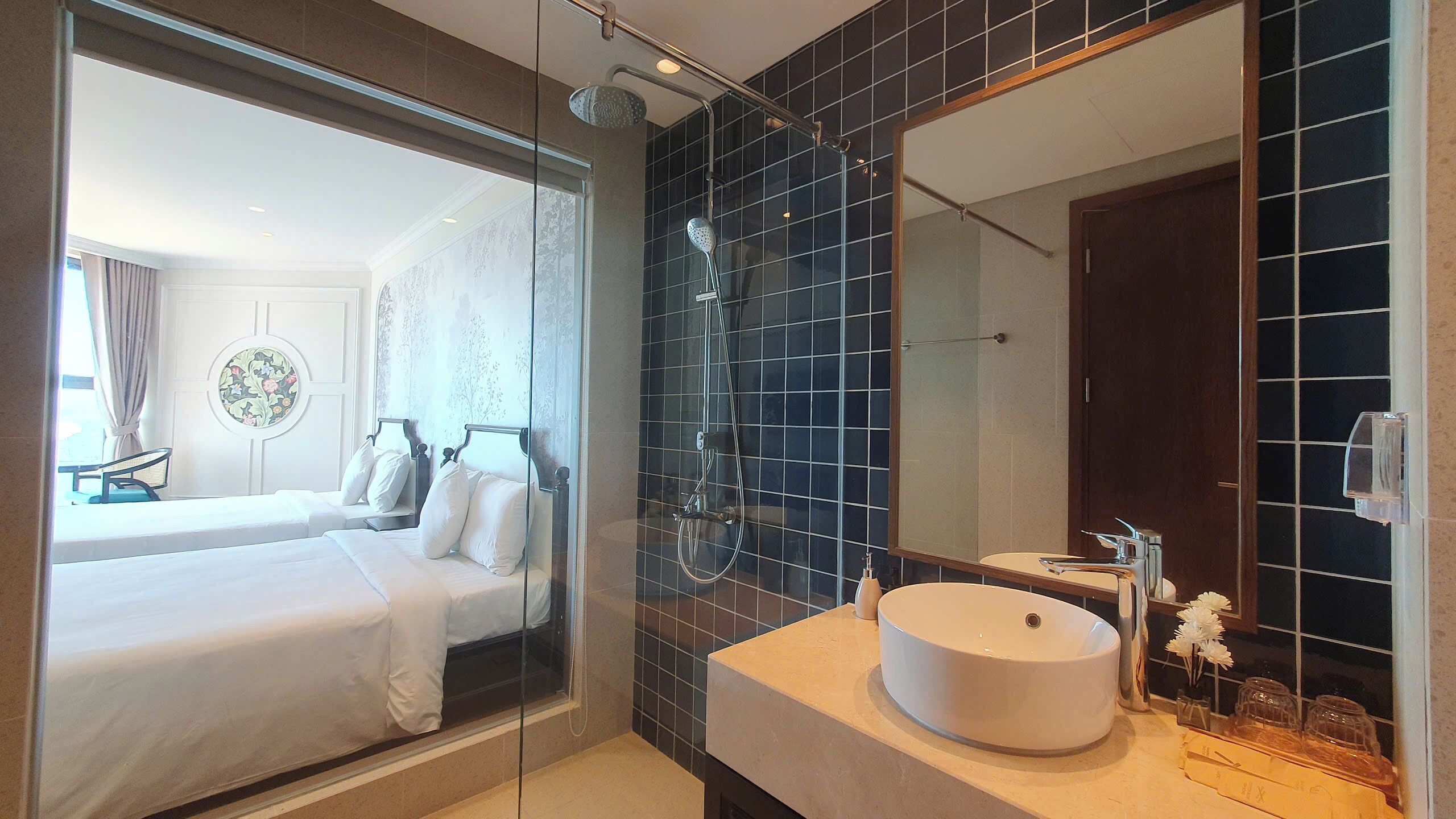 A modern bathroom with a large mirror, a round sink, and a shower.