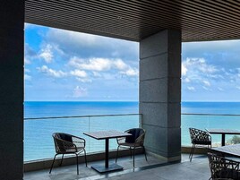A terrace with a view of the sea, featuring outdoor seating and a modern architectural design.