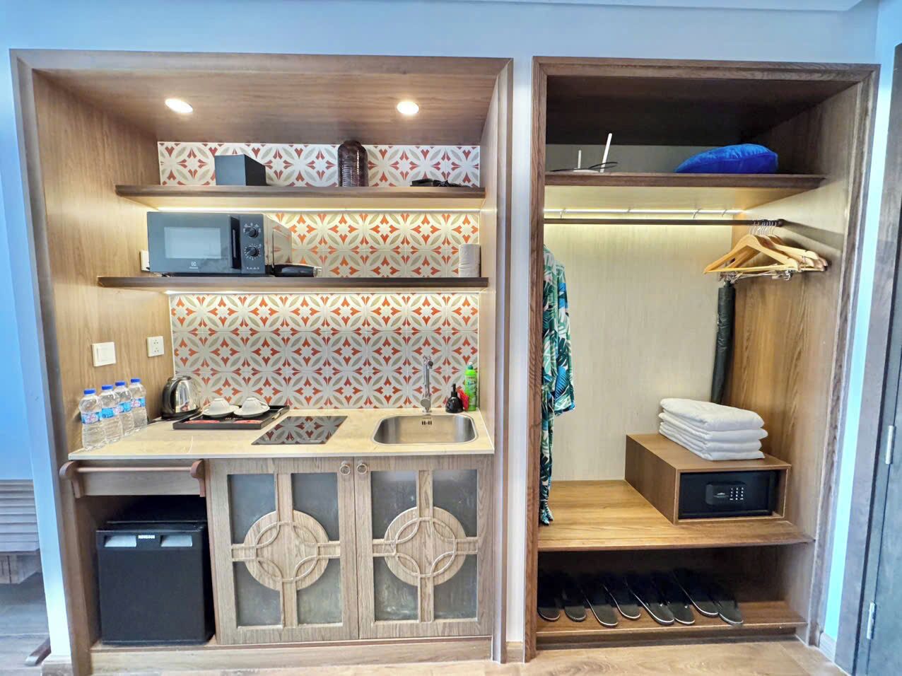 A compact kitchenette with a microwave, sink, and storage shelves.