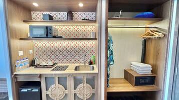 A compact kitchenette with a microwave, sink, and storage shelves.