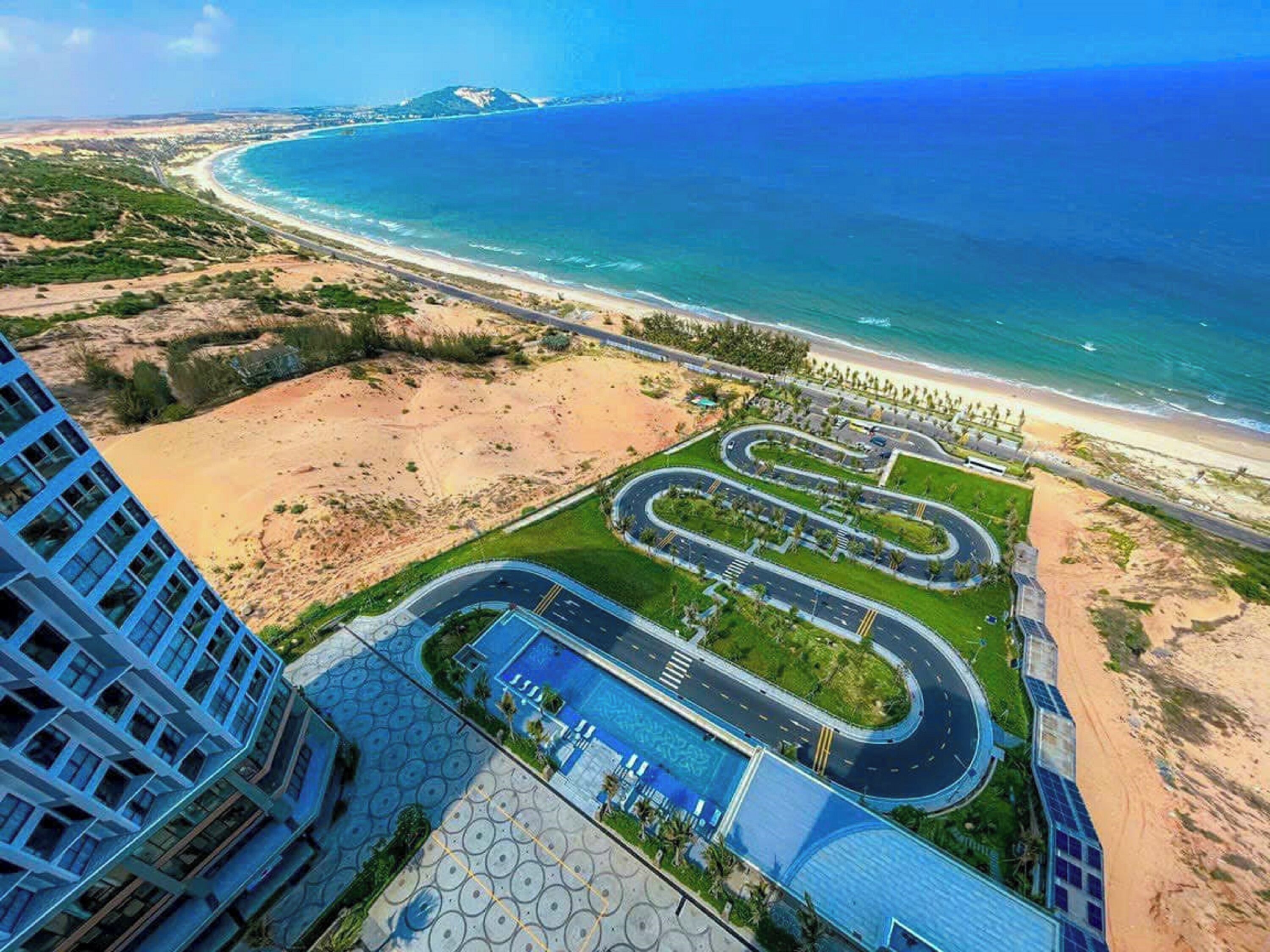 Un hôtel situé sur la côte, avec une route sinueuse, une plage et une vue sur l’océan.