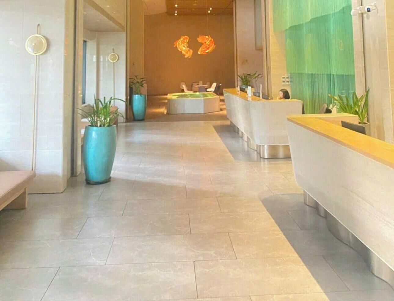 A hotel reception area with a reception desk, seating area, and a wall with a unique light fixture.