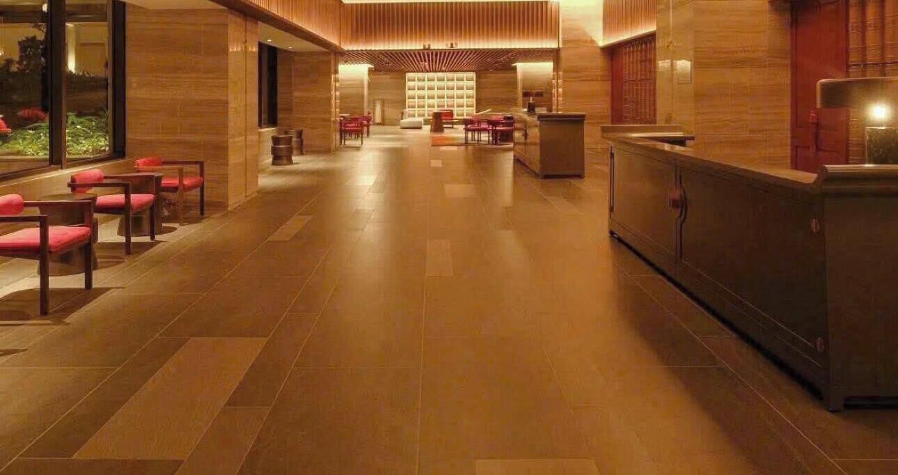 Vestíbulo de hotel con mostrador de recepción, zona de estar y vistas al exterior.
