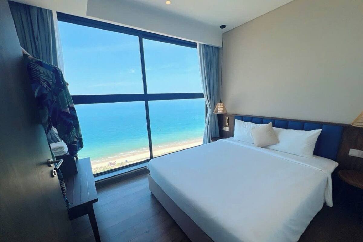 Une chambre d’hôtel dotée d’une grande fenêtre donnant sur la plage et l’océan.