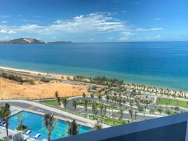 A resort with a pool, palm trees, and a view of the beach and ocean.