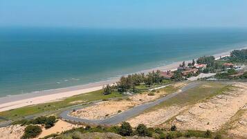 A coastal landscape with a beach, a road, and scattered buildings.