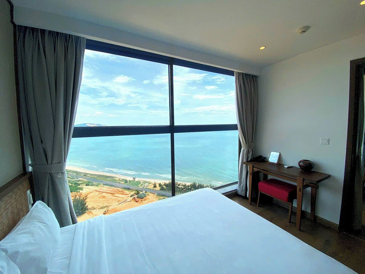 Une chambre d’hôtel avec un grand lit, un bureau et une vue sur l’océan.