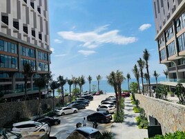 A parking lot with cars, palm trees, and modern buildings with large windows.