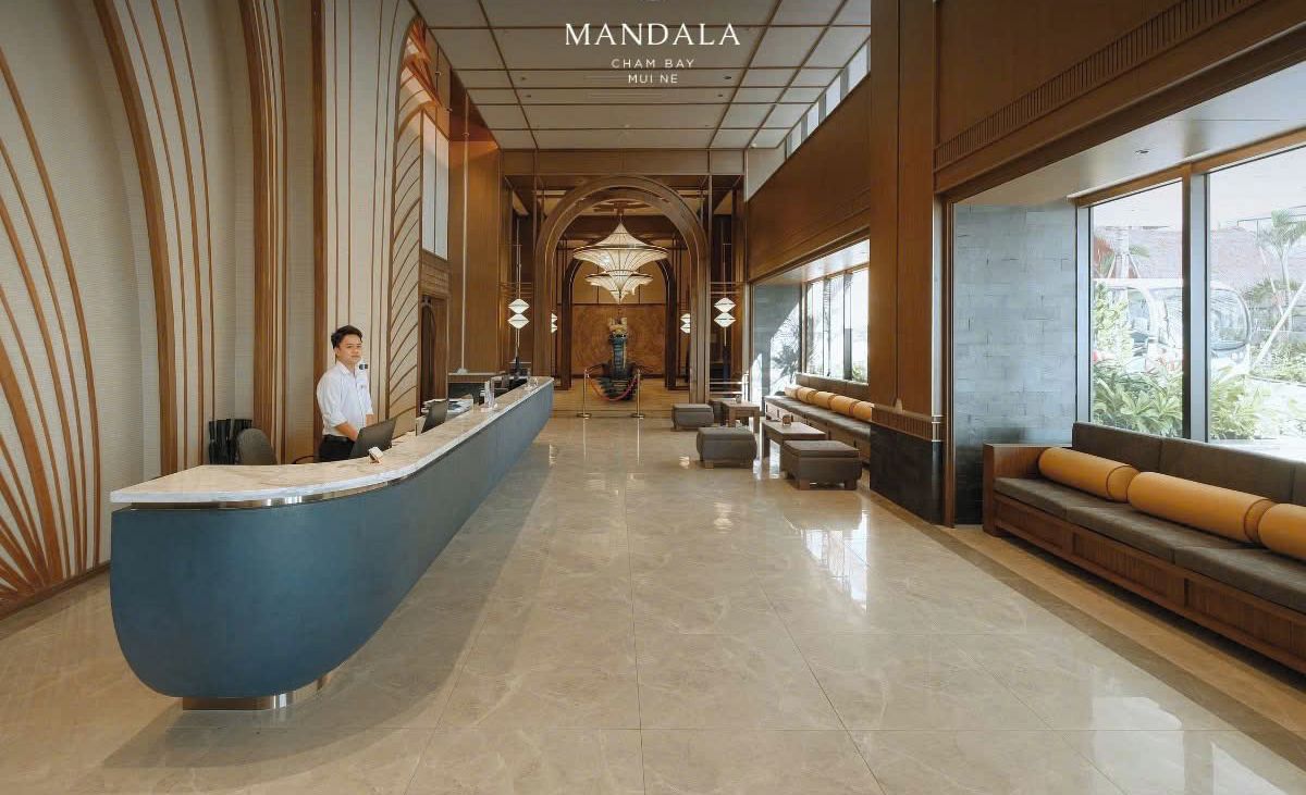 A hotel lobby with a reception desk, seating area, and large windows.