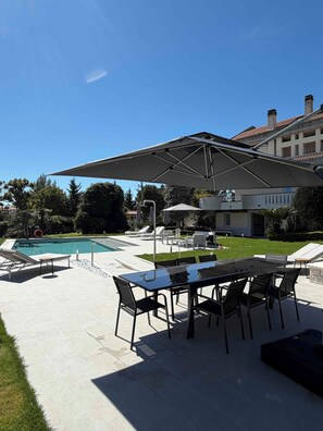 A patio with a pool, outdoor seating, and a large umbrella.