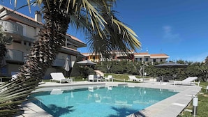 A swimming pool with lounge chairs, palm trees, and a clear blue sky. - Villa Monaco: Double Room in Villa with Pool, Hot Tub (Mosciano Sant'Angelo)