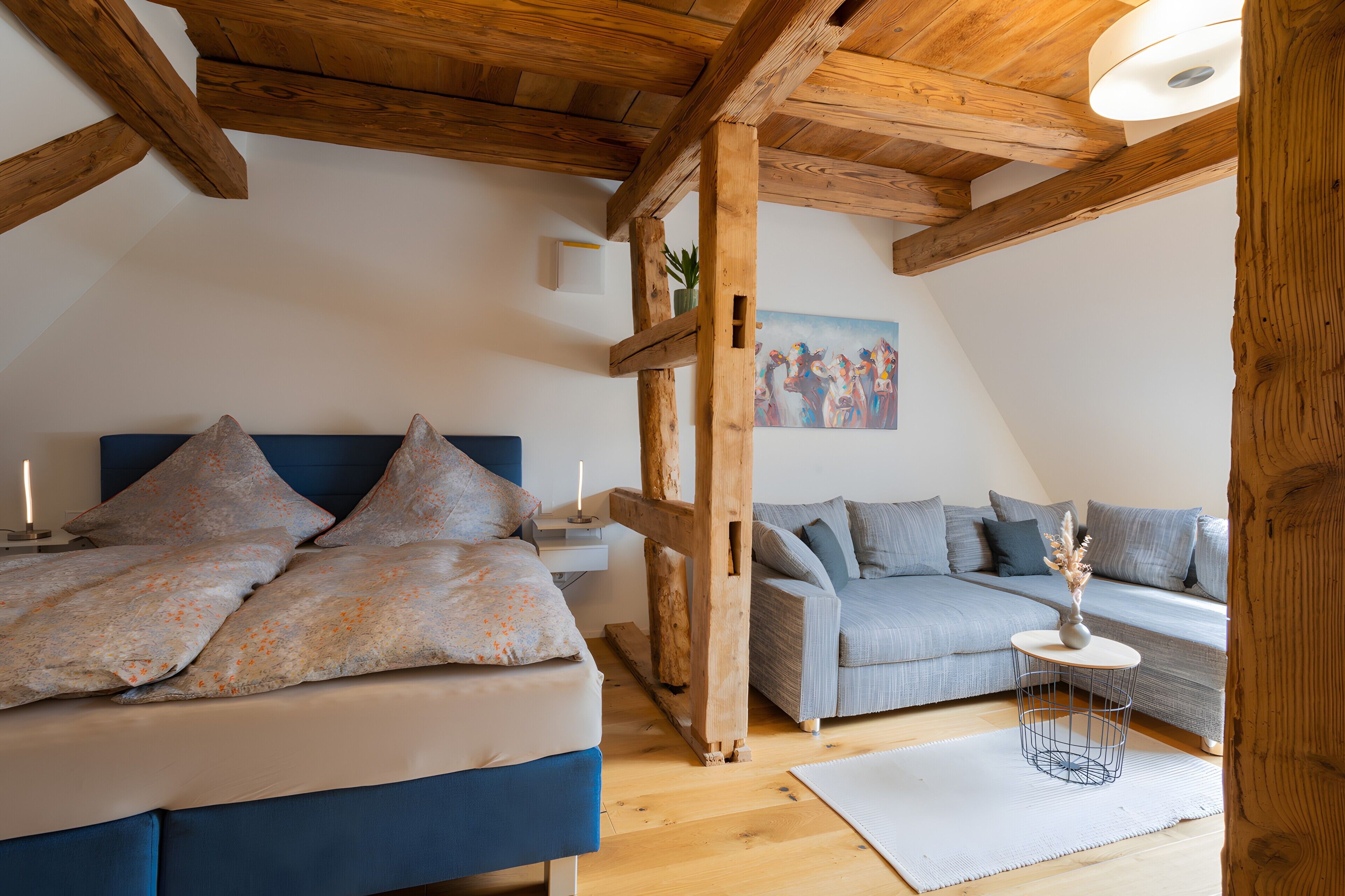 Een slaapkamer met een bed, een bank, een bijzettafeltje en een schilderij aan de muur.
