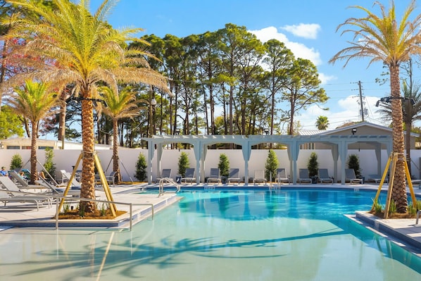 A swimming pool with lounge chairs and palm trees.