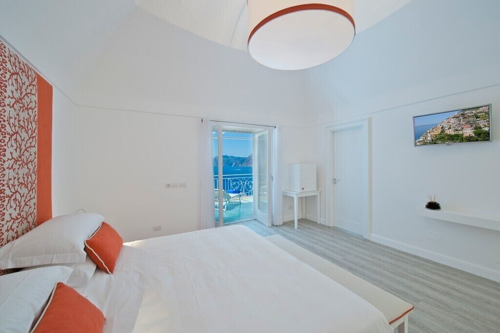 Una habitación de hotel moderna con una cama grande, un balcón con vistas y un cuadro en la pared.