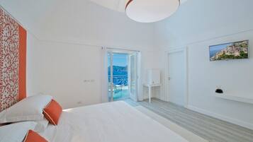 Una habitación de hotel moderna con una cama grande, un balcón con vistas y un cuadro en la pared.