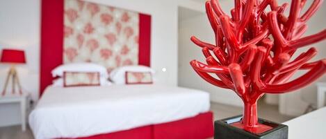 Un dormitorio moderno con una cama, una escultura abstracta roja y un cabecero estampado en rojo y blanco.