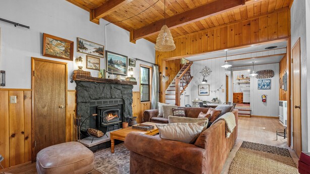 Ein gemütliches Wohnzimmer mit Kamin, Holzmöbeln und einer Treppe, die in einen anderen Raum führt.