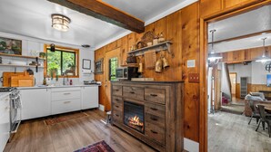 Eine Küche mit Holzausstattung, einem Kamin und einem Essbereich mit Tisch und Stühlen.