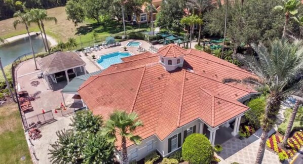 A large house with a red-tiled roof, a swimming pool, and a covered patio area.