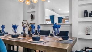 Comedor con mesa de madera dispuesta para cuatro personas, cristalería azul y sillas a juego.