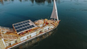 A large, luxurious yacht with a spacious deck, multiple levels, and a prominent sail.