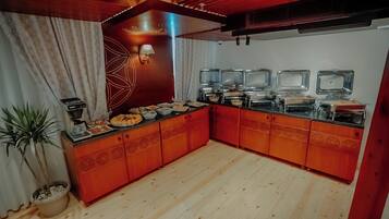 A kitchen with wooden cabinets, a coffee machine, and a buffet setup with multiple serving dishes.