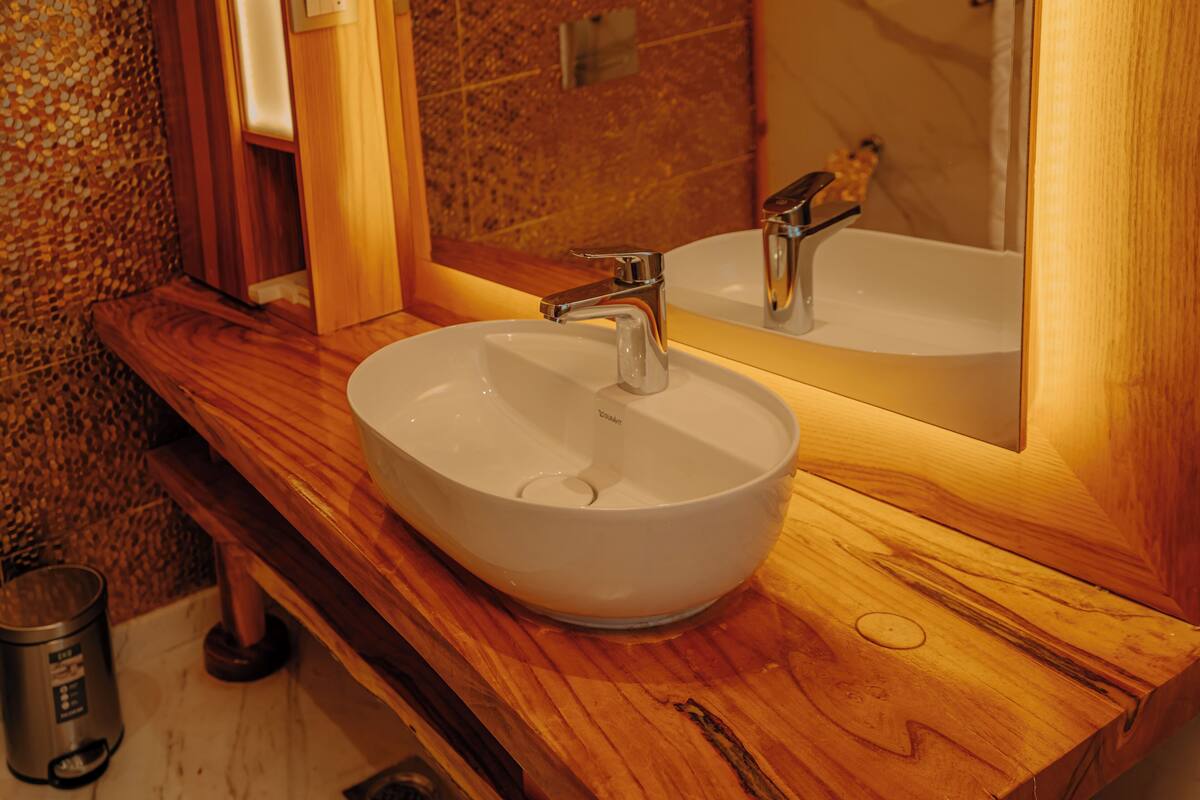 Ein Badezimmer mit einem Holzbadezimmermöbel, einem weißen Waschbecken und einem Spiegel.