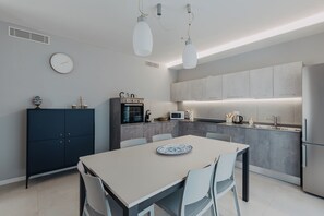 Une cuisine moderne avec coin repas, dotée d’un four encastré, d’un four à micro-ondes et d’appareils électroménagers en acier inoxydable.