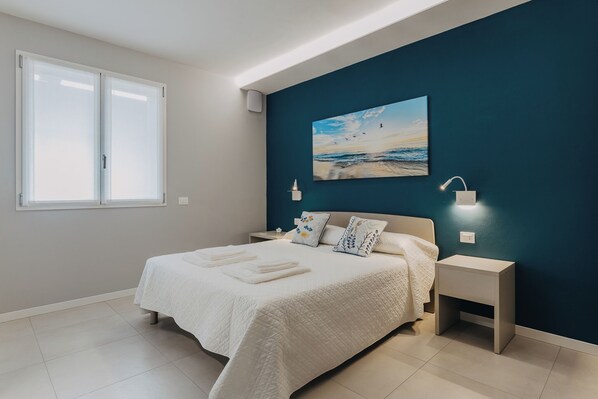 Une chambre à coucher avec un lit, des tables de chevet, un tableau et une fenêtre.