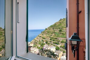 A balcony with a view of a coastal landscape, a lamp post, and a window with a visible handle. - Apartment 'Dolphin' with Sea View and Wi-Fi (Manarola)