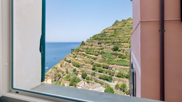 A coastal view from a window, including a hillside with buildings and a clear sky.