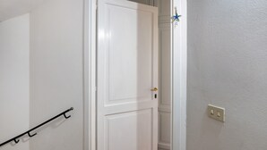 A white door with a gold handle, a black metal rack, and a light switch on the wall.