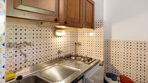 A kitchen with wooden cabinets, a gas stove, and patterned tile backsplash.