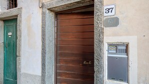 A brown wooden door with a metal handle, a green door to the left, and a utility box with a sign above it.