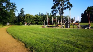 A park with a dirt path, playground equipment, and trees. - Holiday Home for 4 "La Marguerite" Countryside Gite near Puy du Fou (Les Herbiers)