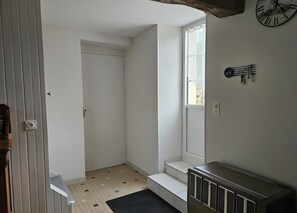 A small, clean room with a radiator, a window with a view, a door, and a wall clock.