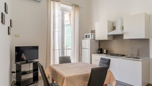 Una cocina compacta con una mesa de comedor, sillas, un televisor sobre un mueble, un microondas y un lavabo.