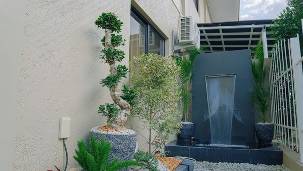 A modern outdoor space with a water feature, potted plants, and a stone pathway. - Executive 2-bedroom condo in Subic Bay Freeport Zone (Subic Bay Freeport Zone)