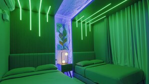 A room with two beds, green bedding, a nightstand with a lamp, and green neon lighting. - Executive 2-bedroom condo in Subic Bay Freeport Zone (Subic Bay Freeport Zone)