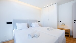 Una moderna camera d'albergo con due letti, un comodino con una lampada e un armadio.