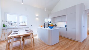 Una cucina moderna con isola centrale, tavolo da pranzo in legno e sedie.