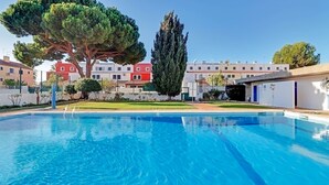 Una piscina con agua cristalina azul, rodeada por un césped cuidado y árboles.