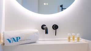 A bathroom with a white sink, a towel with "VAP" and "HOLIDAY RENTALS" text, and three toiletries on the counter.
