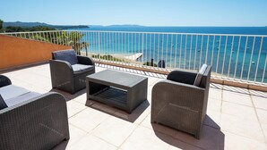 Una terraza con mobiliario de mimbre y vista al mar.