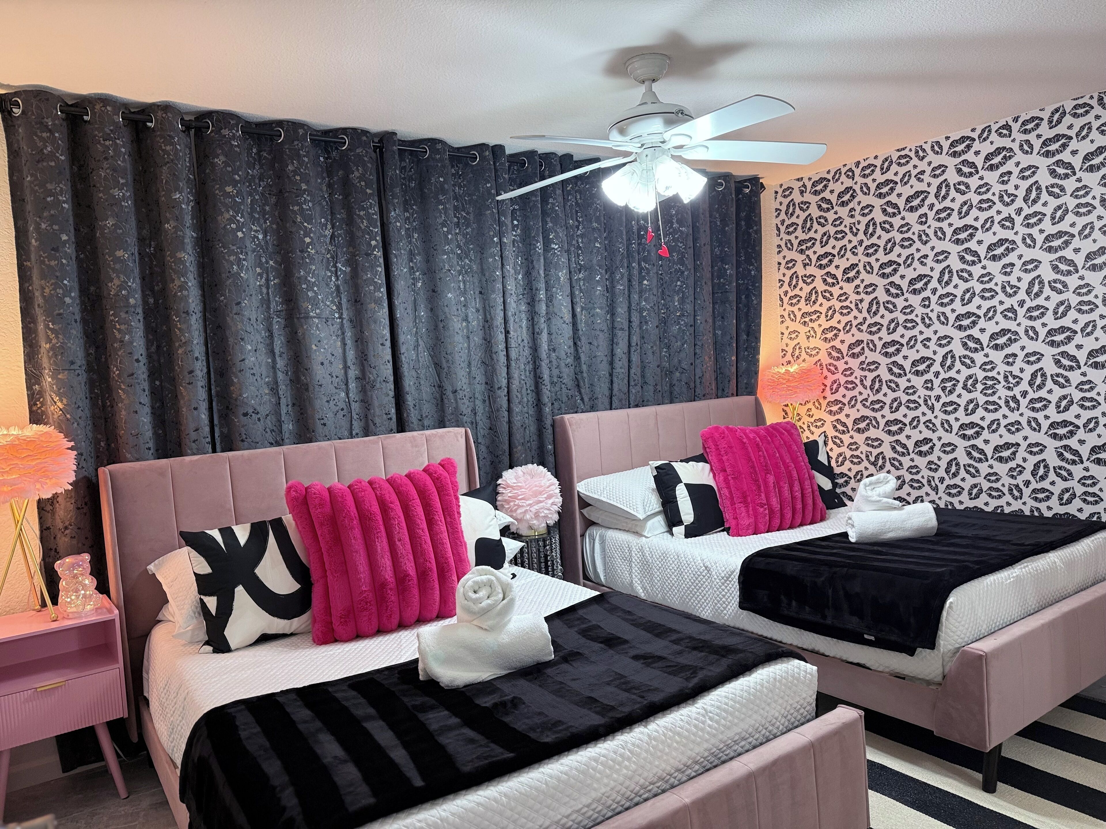 A hotel room with two beds, a ceiling fan, and a patterned wallpaper.