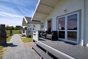 A modern outdoor deck area with seating and a barbecue grill. - Family Holiday Homes, Playground, Summer Pool (Ustronie Morskie)
