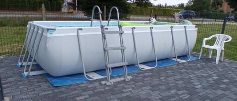 Une piscine hors sol, équipée d’une échelle et d’une chaise.