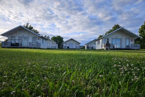 Una hilera de casas móviles blancas iguales con un campo césped en primer plano.