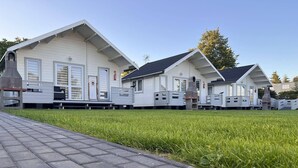 Uma fileira de casas móveis brancas com telhados inclinados e um calçada pavimentada na frente.