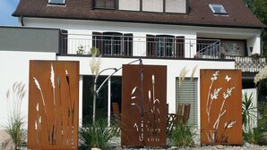 Une maison moderne à deux étages, dotée d’un toit en pente, de grandes fenêtres et d’un balcon.